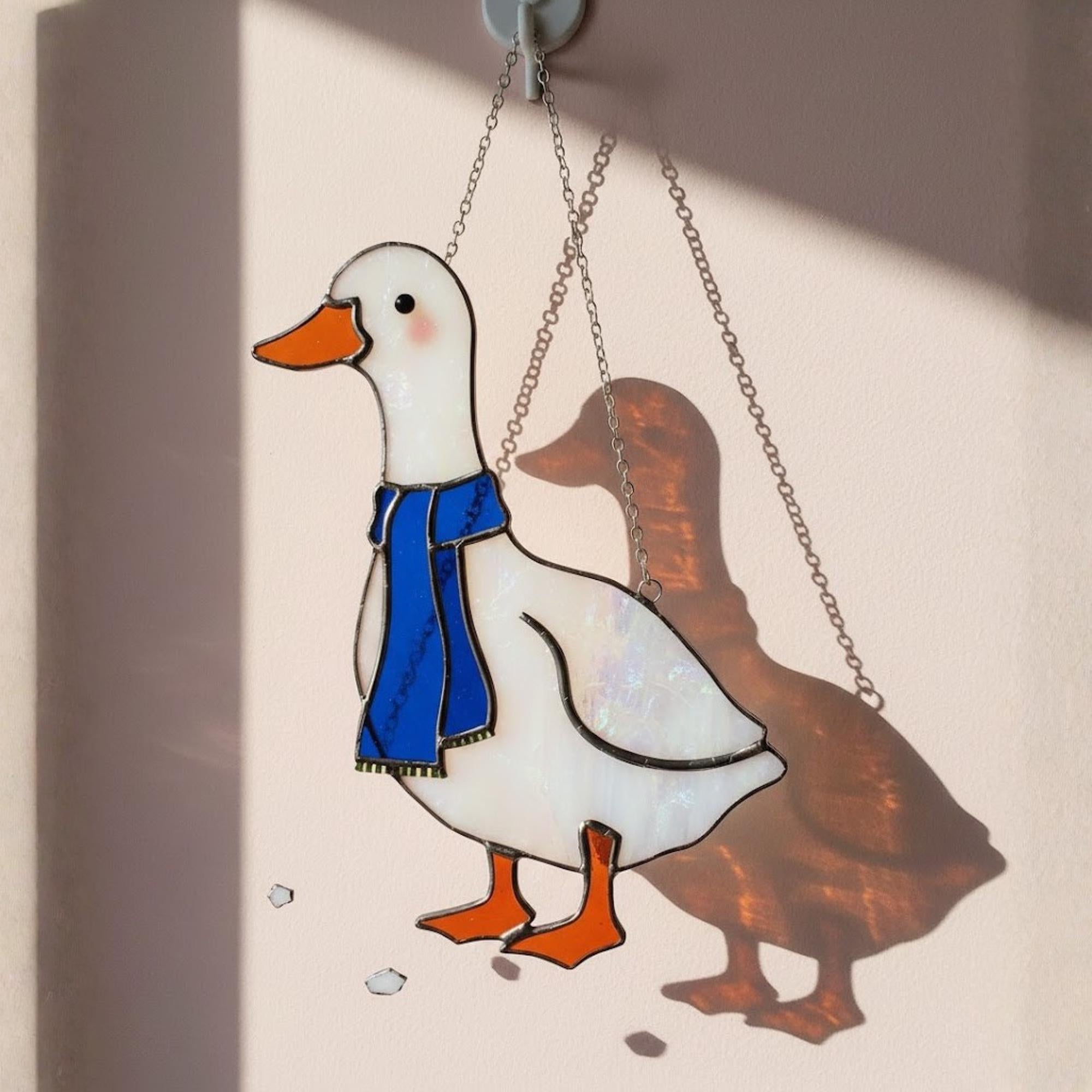 Stained glass goose hanging on window with warm afternoon light, handmade décor
