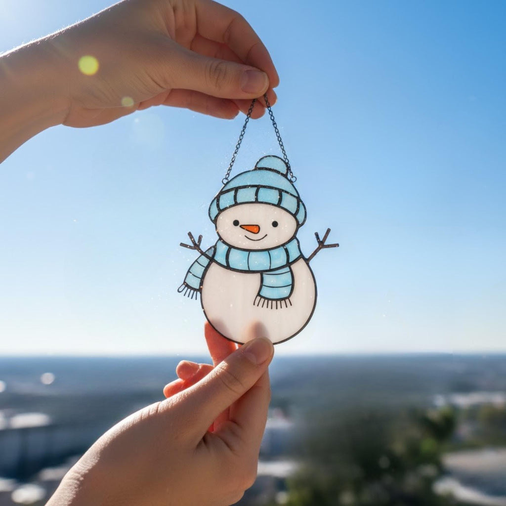 Handmade stained glass snowman ornament glowing by window sunlight – festive winter home decoration.
