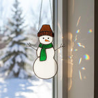 Hanging stained glass snowman glowing with warm sunlight – home decor for winter holidays.