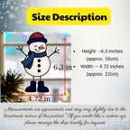 A hand holding a stained glass snowman suncatcher  outdoors against a blurred house background.