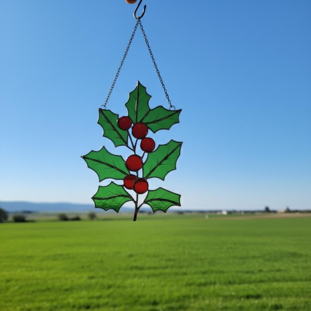 Pair of holly leaf suncatchers displayed outdoors — handmade green glass art.