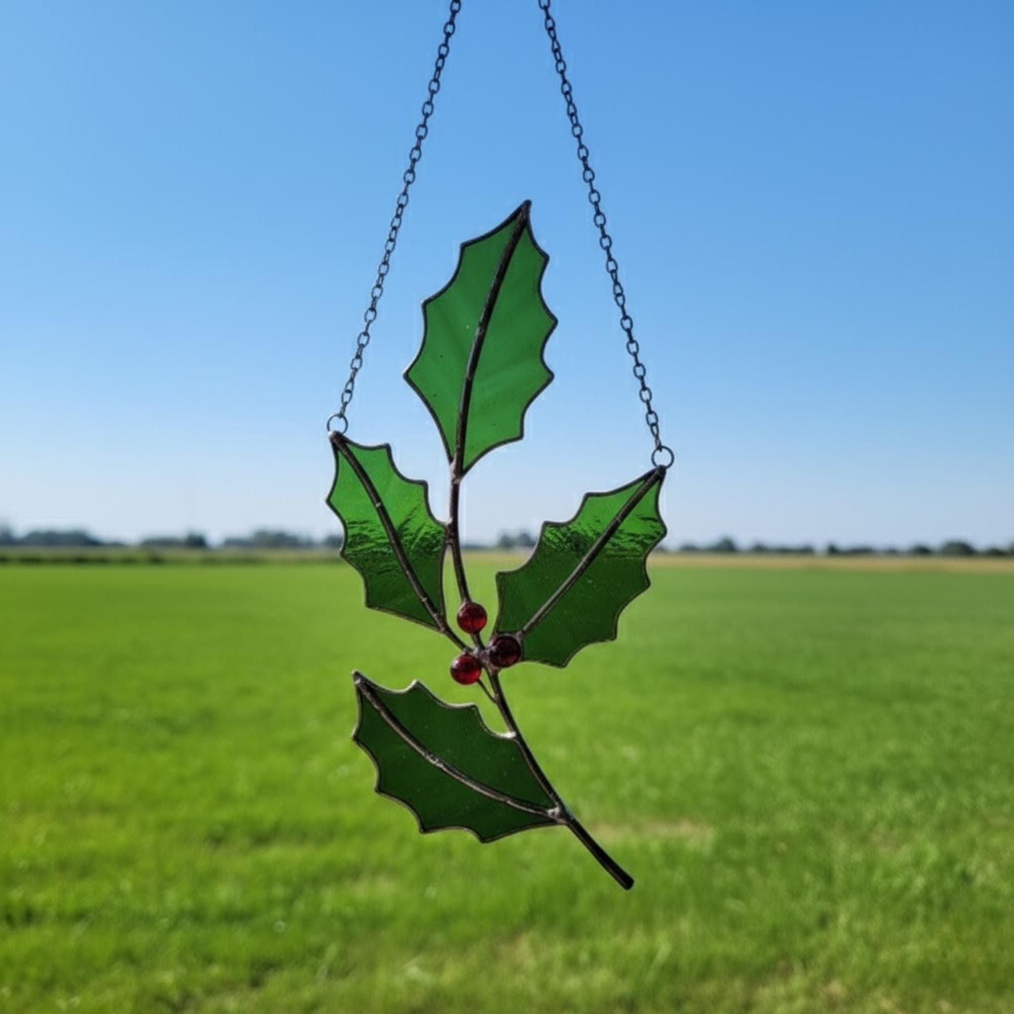 Holiday-themed glass mistletoe suncatcher — green leaves with red berry design.