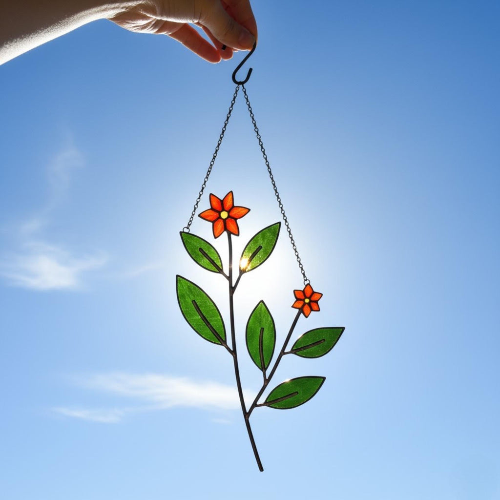 Red and green stained glass Christmas ornament glowing in sunlight.