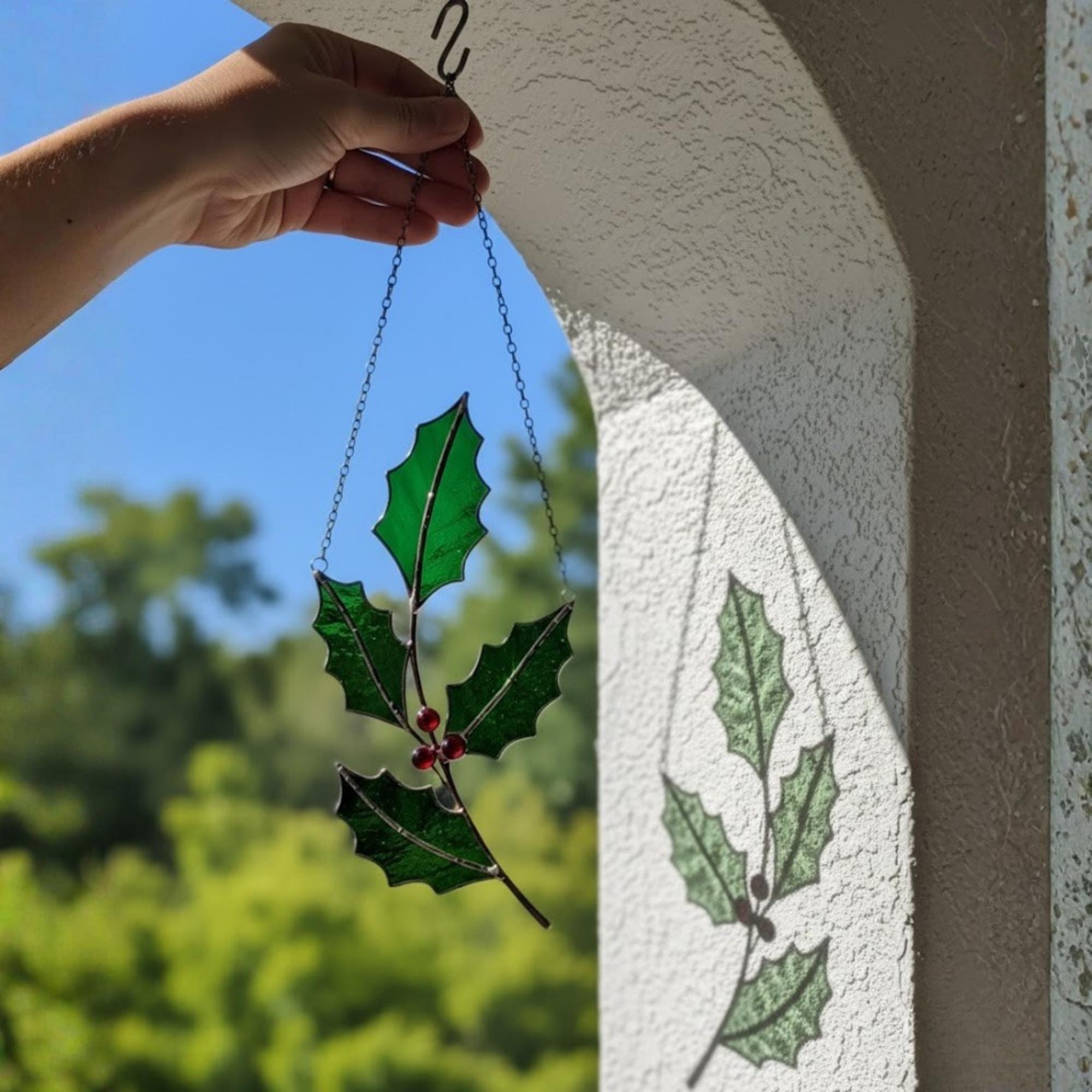 Collection of floral and holly leaf glass suncatchers hanging together.