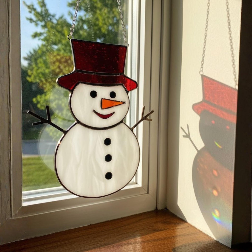 Snowman ornament with blue hat shining on window ledge in winter light.