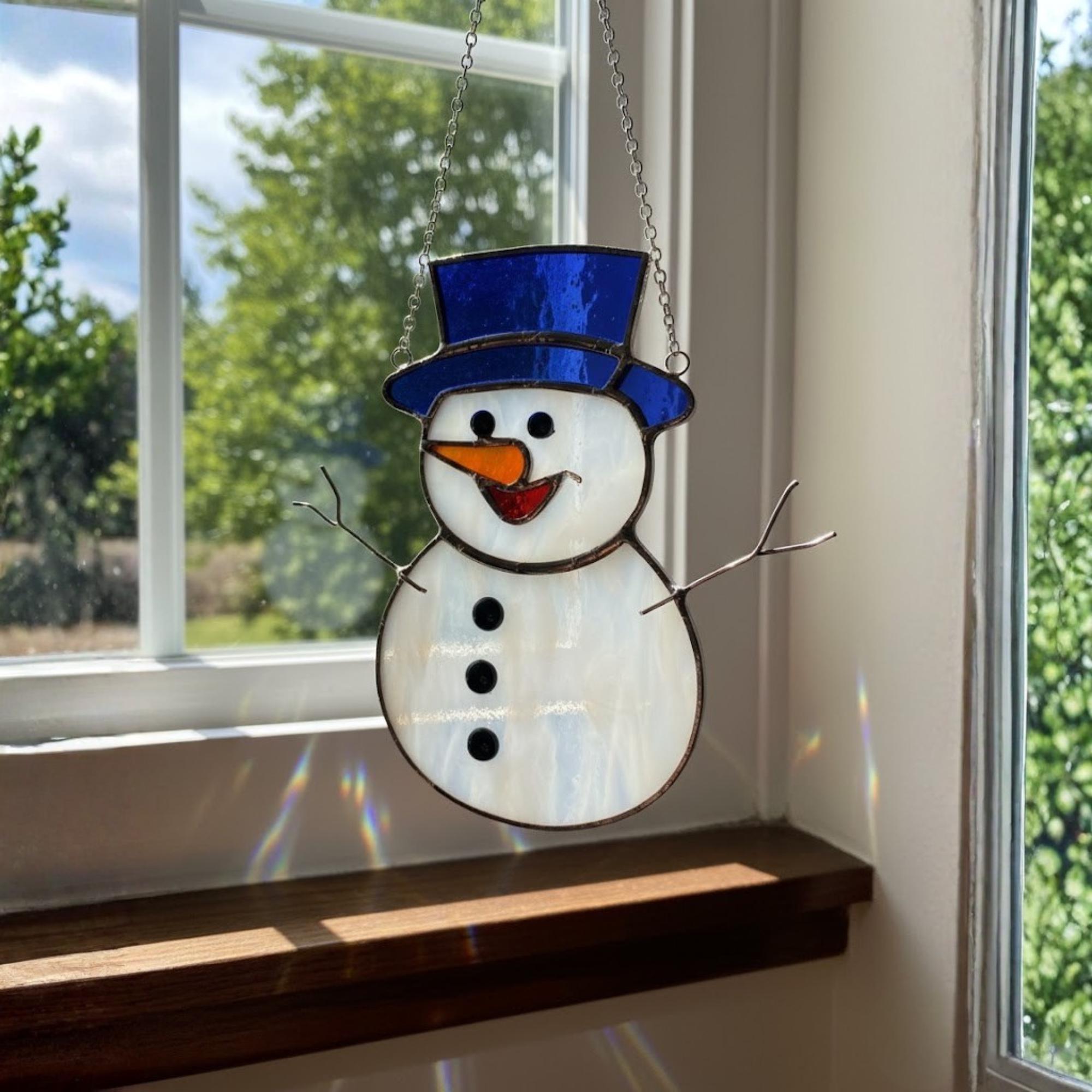 Family hanging snowman suncatchers on window together during Christmas.