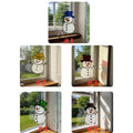 Black hat handmade glass snowman suncatcher glowing under bright sun.