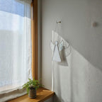 Handmade guardian angel stained glass hanging outside wall reflecting sunlight.