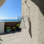 Stained glass angel with textured wings displayed as window art catching gentle daylight.