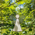Memorial glass angel ornament symbolizing love and remembrance by a sunny window.