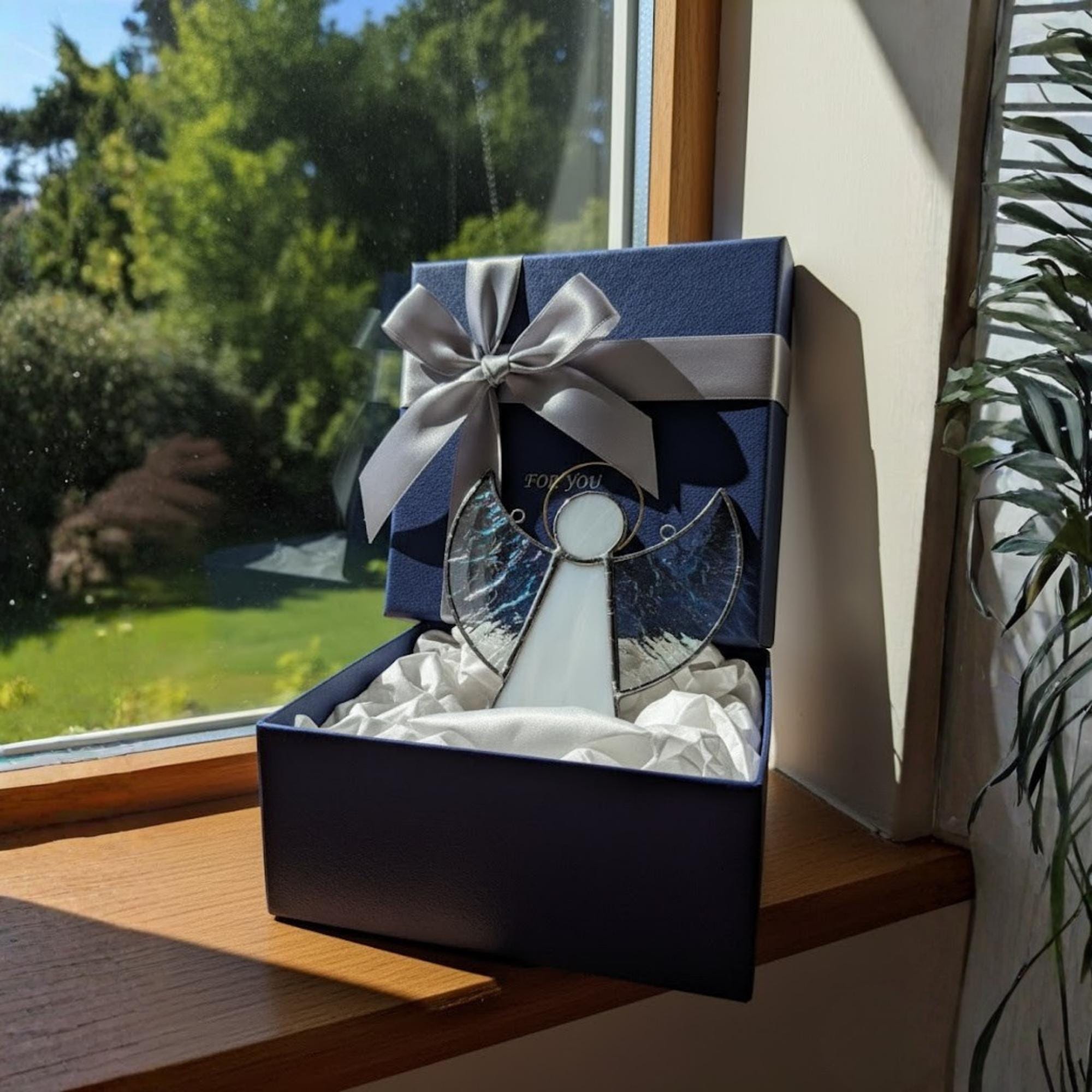 Close-up of elegant stained glass angel suncatcher reflecting natural light near a window.