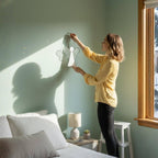 Woman holding handmade stained glass angel suncatcher with glowing reflections on the wall.