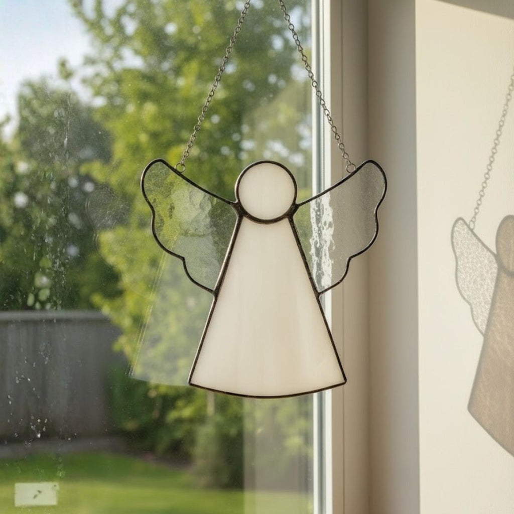 Transparent angel suncatcher creating beautiful light patterns on wall and glass.