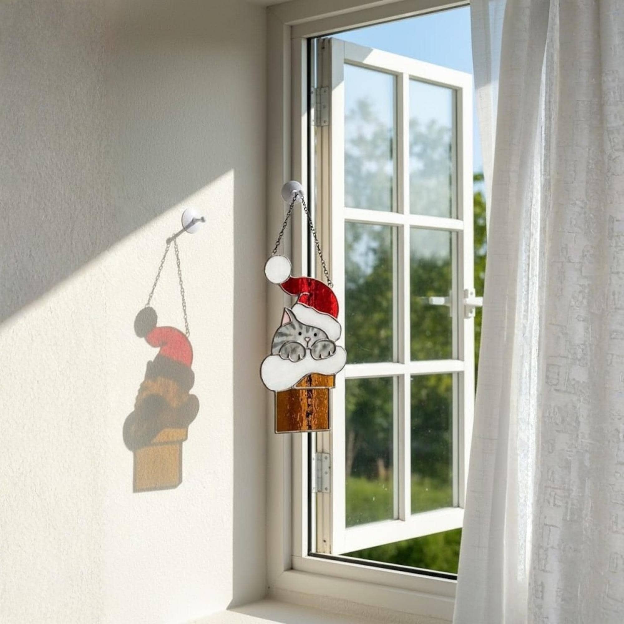 Handmade stained glass Christmas cat ornament with Santa hat held in sunlight, perfect festive gift for cat mom and pet lover