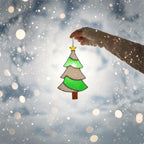 Stained glass Christmas tree ornament held in snowy scene, winter holiday photo