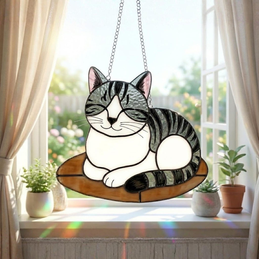Stained glass cat suncatcher capturing sunlight on window sill, bright window decor.