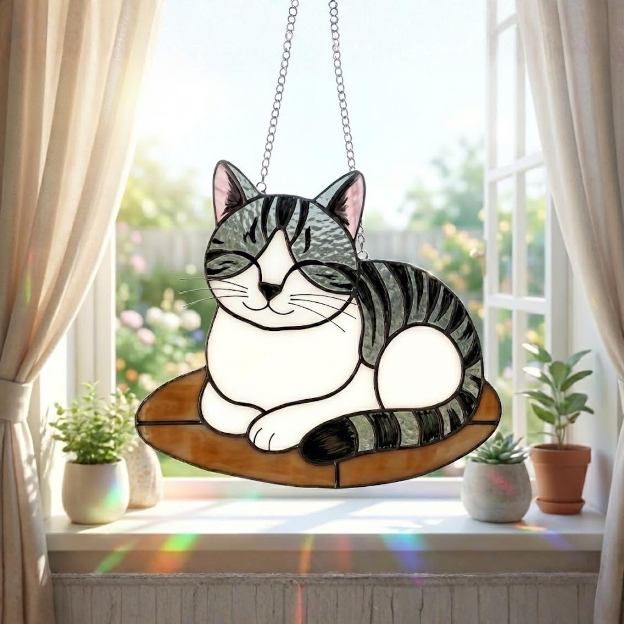Stained glass cat suncatcher capturing sunlight on window sill, bright window decor.
