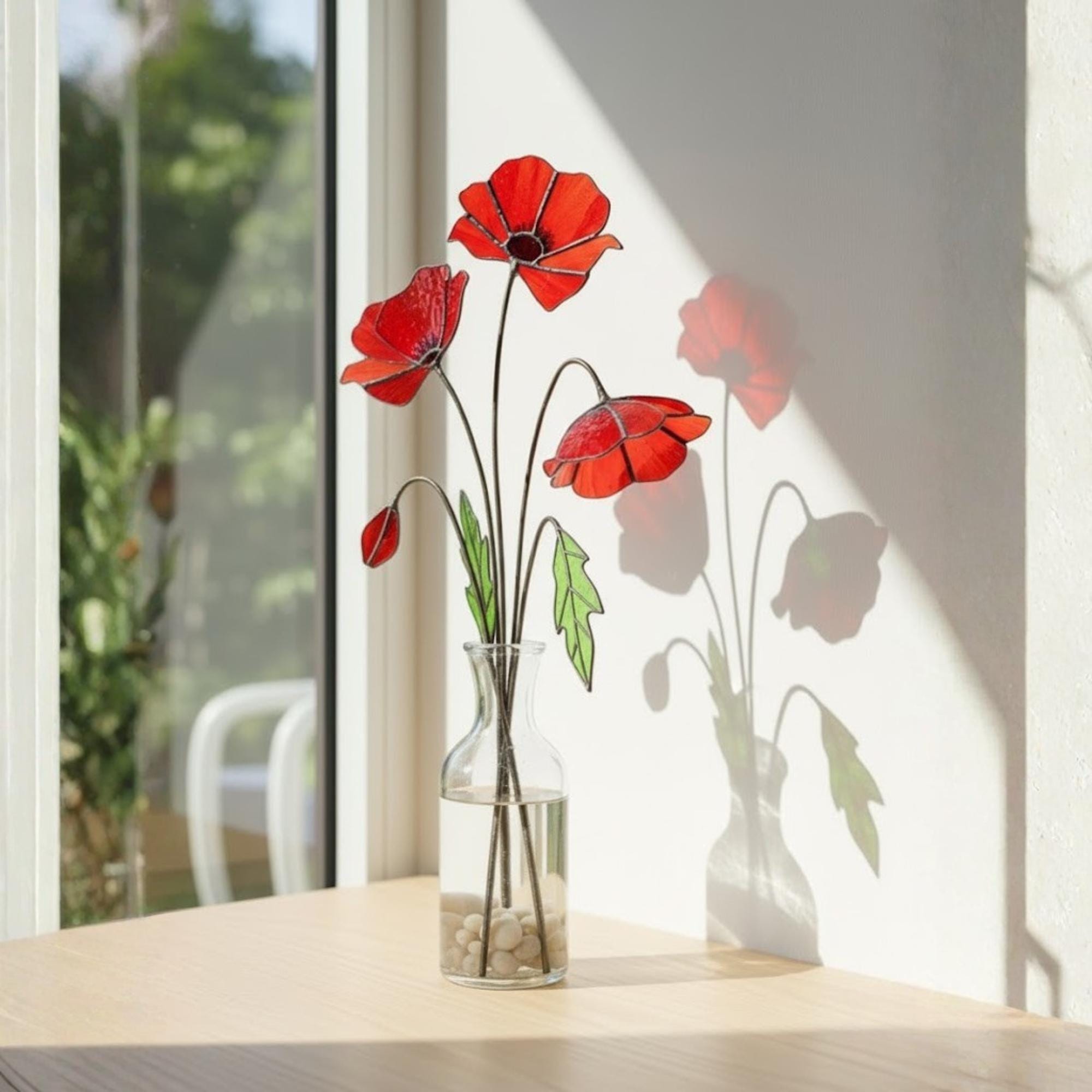 Three stained glass poppy stems in vase with bright natural light