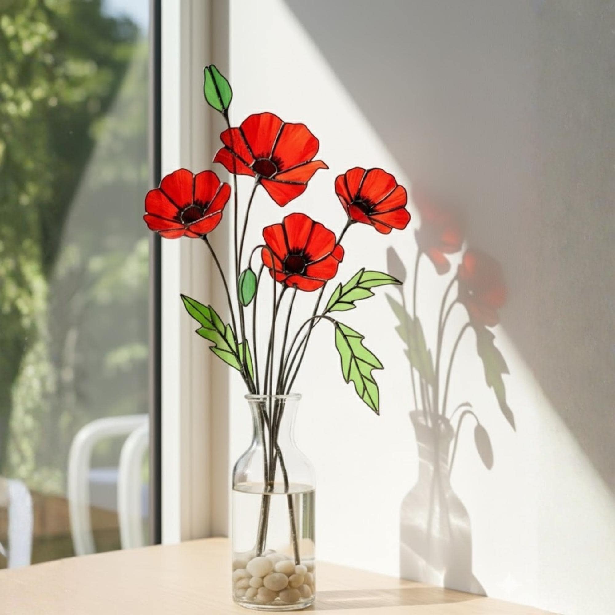 Four stained glass poppy stems displayed indoors with natural sunlight