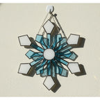 Detailed stained glass snowflake hanging on wall, icy blue winter decoration