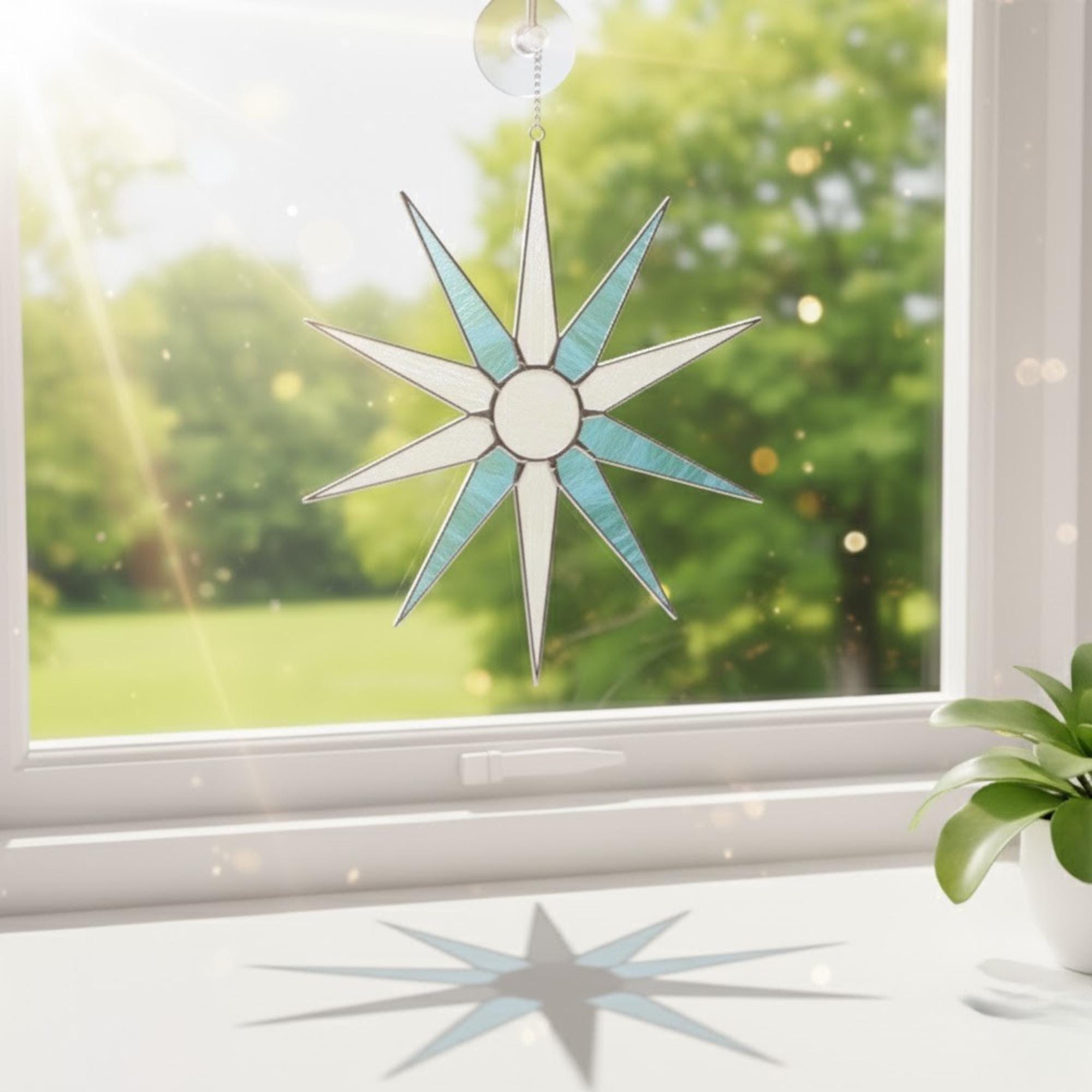Stained glass snowflake shining in sunlight on window sill, home decor