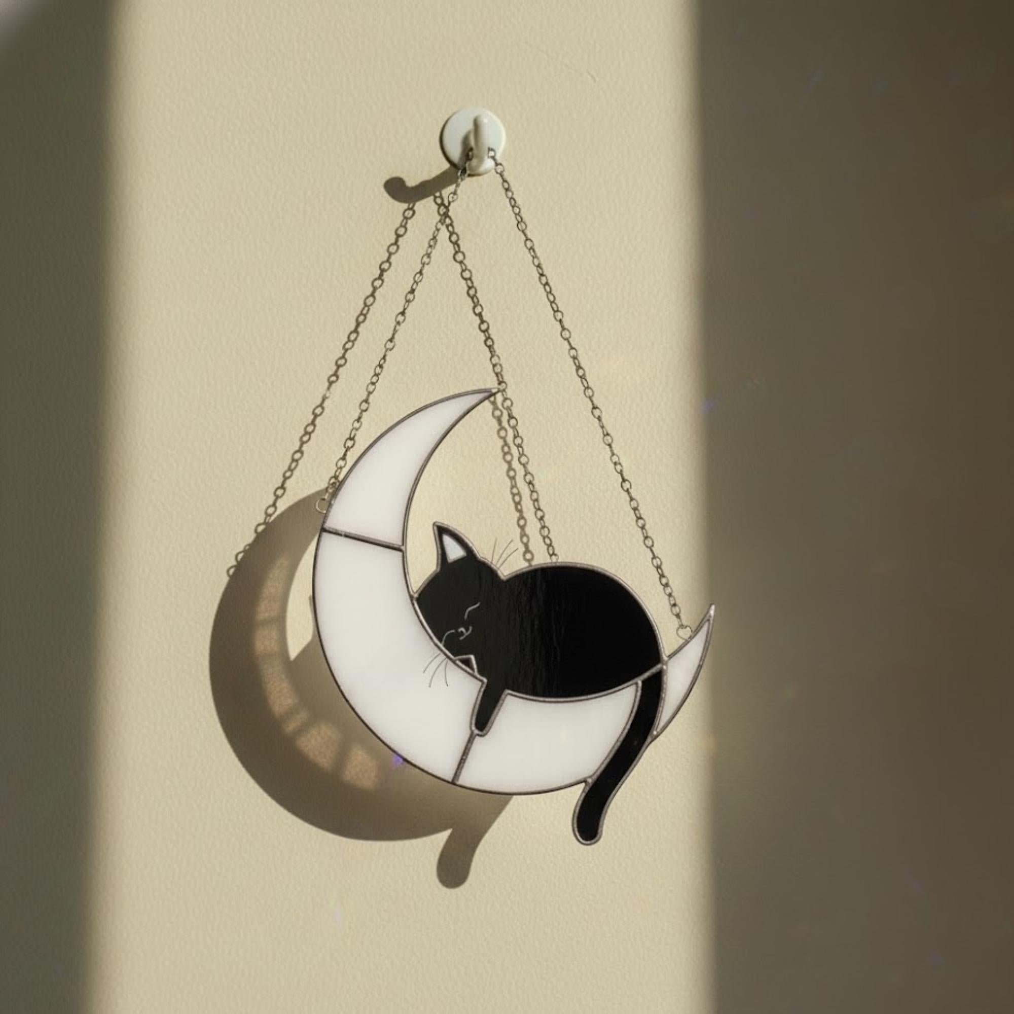 Stained glass moon cat glowing on window sill at sunset, celestial home decor