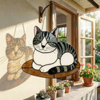 Stained glass cat hanging on window frame with beautiful shadow projection on wall.