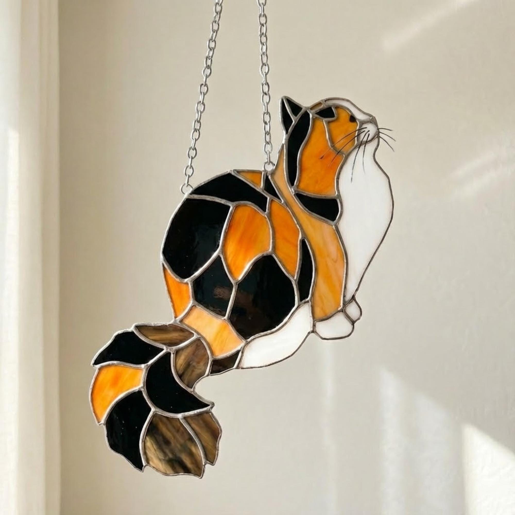 Stained glass Calico cat suncatcher with orange black and white patches, available in sitting and sleeping poses, window hanging or wood stand decor.
