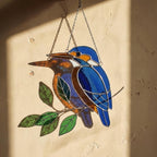 Vibrant stained glass Kingfisher bird suncatcher with blue wings and orange chest perched on a branch, displayed as window hanging or table decor.
