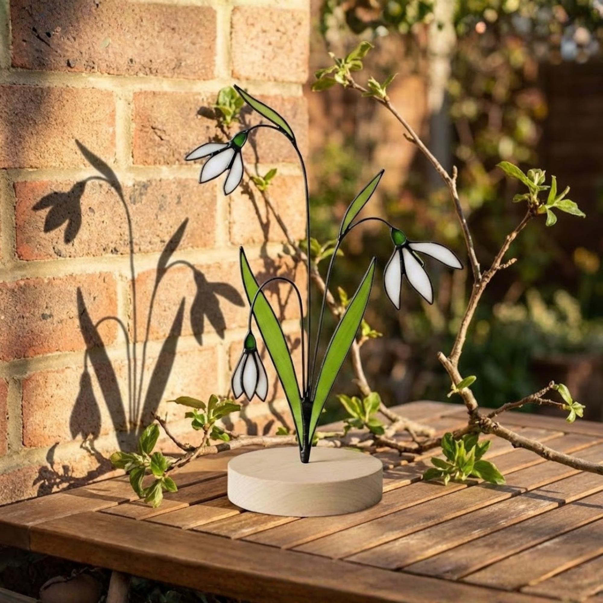 Stained glass snowdrop flower with white petals and green leaves, January birth month gift, available with personalized wood stand or as a single stem.