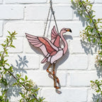 Pink stained glass flamingo suncatcher hanging in window casting vibrant colored shadows tropical beach house decor handmade gift for mom by LuzyGlassArt.