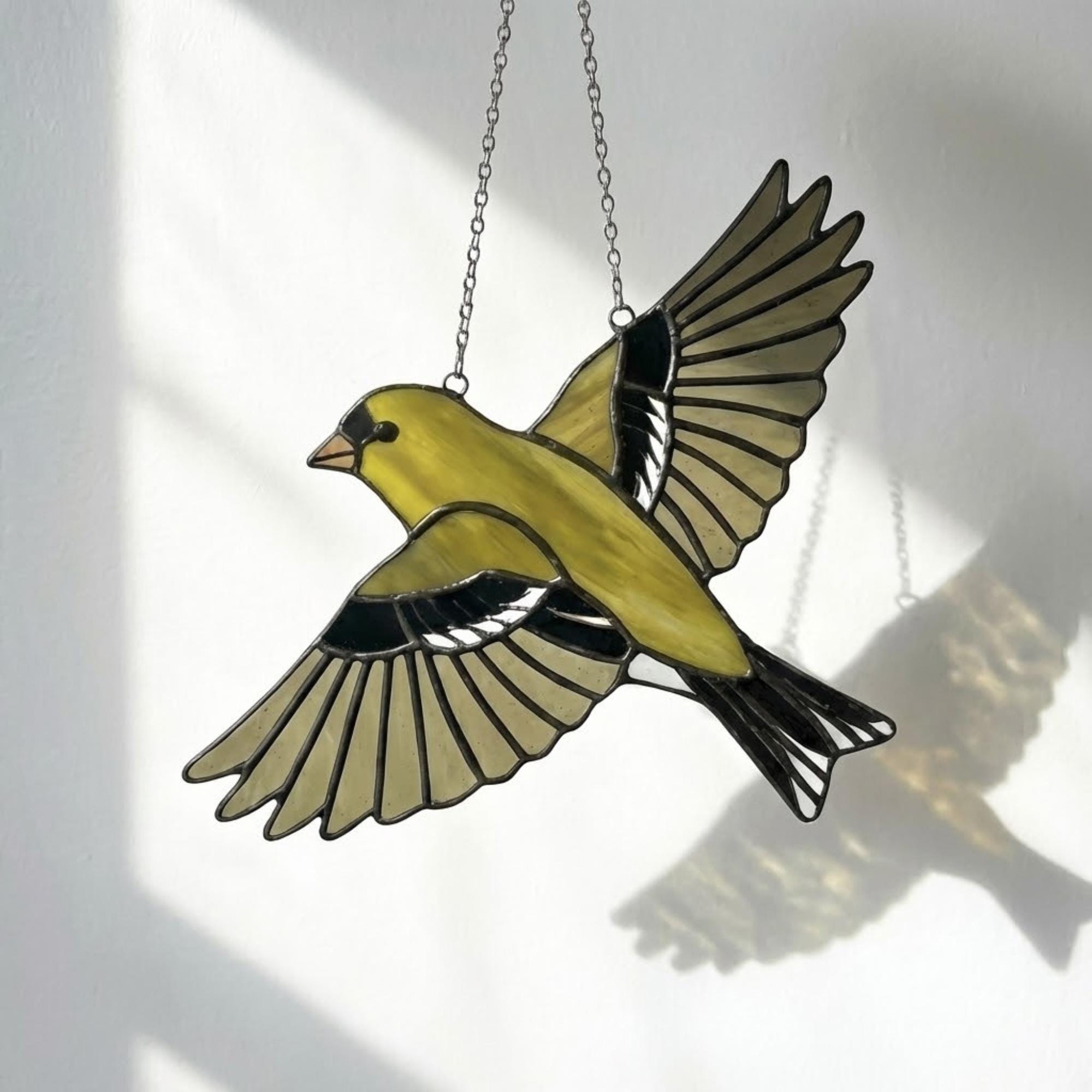 Stained glass American Goldfinch suncatcher hanging on window casting yellow shadows, vibrant yellow bird ornament for birdwatchers, handmade state bird gift for New Jersey Iowa Washington by LuzyGlassArt.