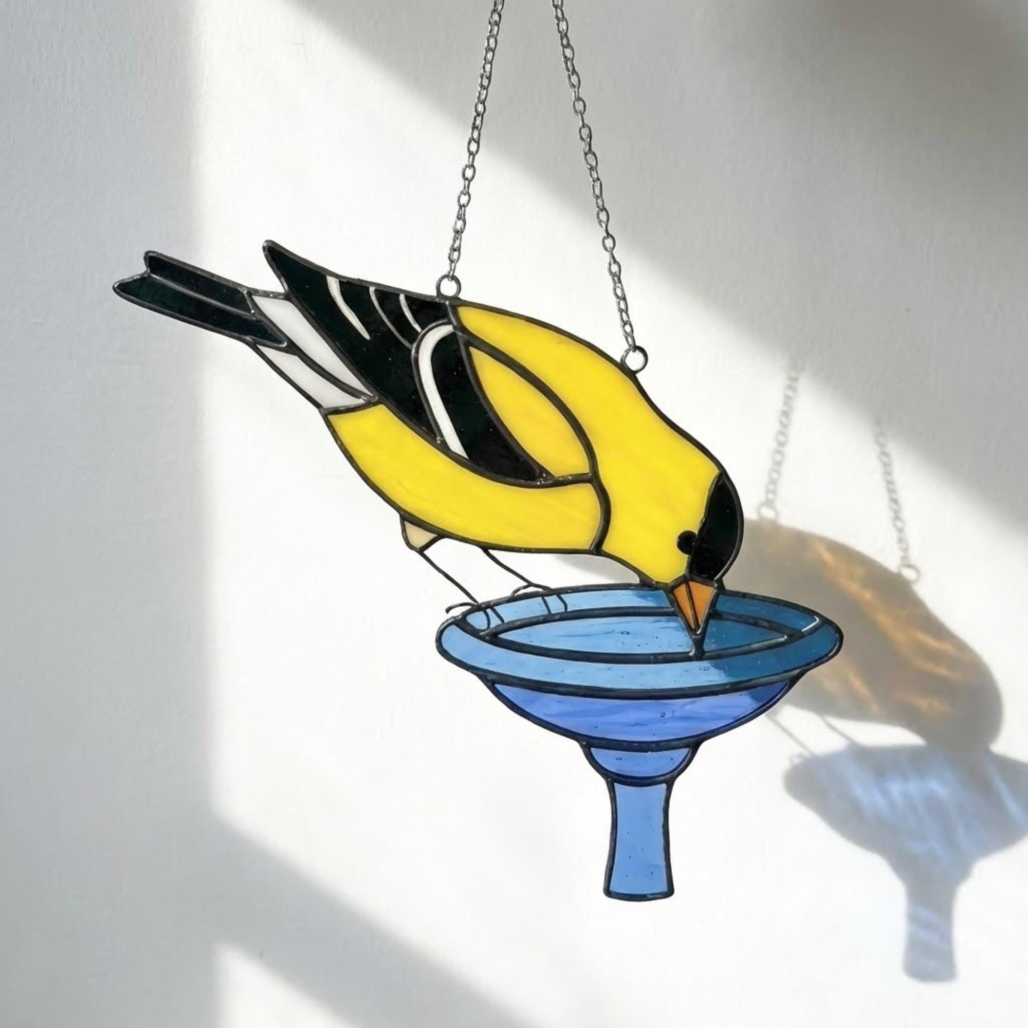 Stained glass American Goldfinch suncatcher hanging on window casting yellow shadows, vibrant yellow bird ornament for birdwatchers, handmade state bird gift for New Jersey Iowa Washington by LuzyGlassArt.