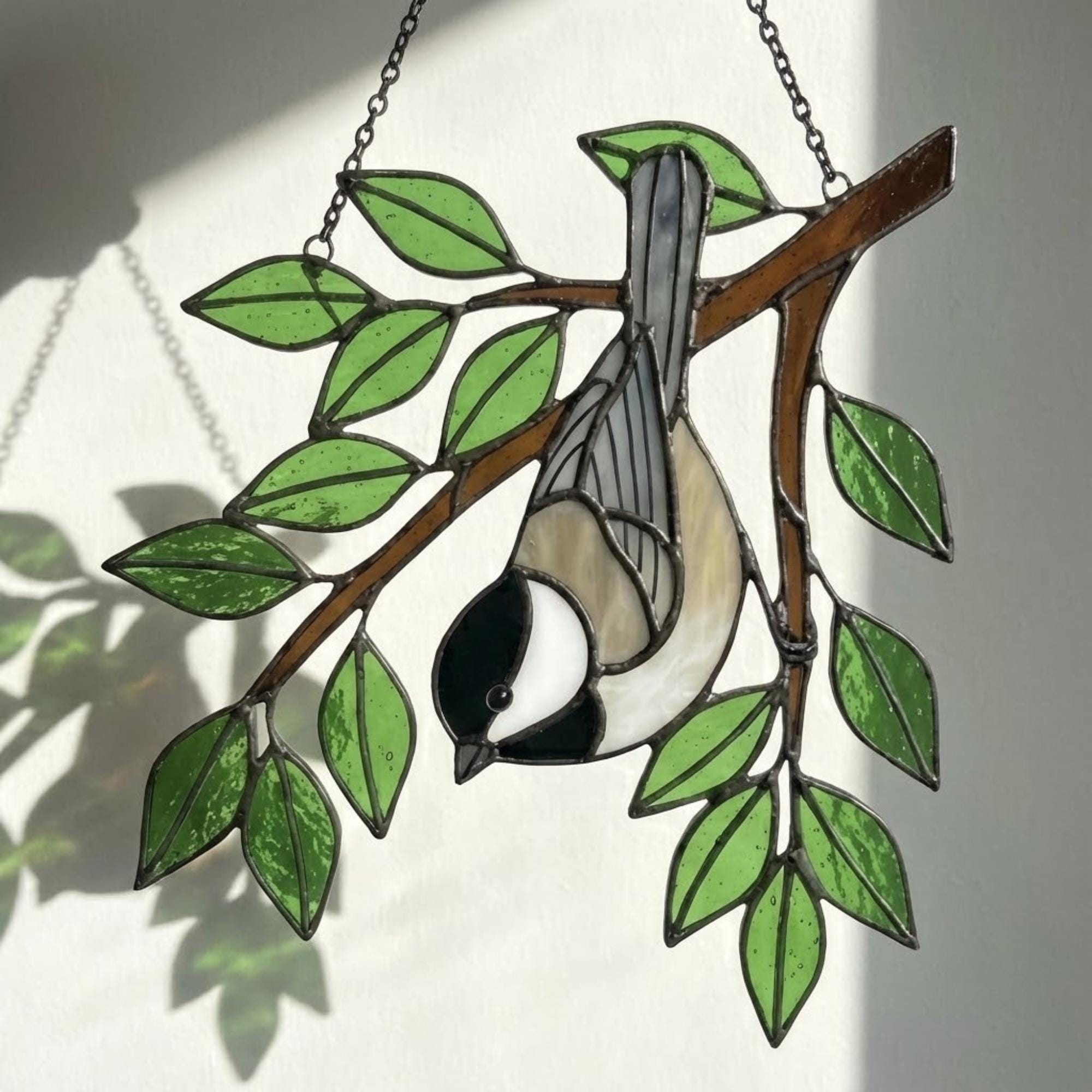Stained glass Black-capped Chickadee bird suncatcher on branch hanging on window, handmade Maine and Massachusetts state bird gift, realistic nature decor by LuzyGlassArt.
