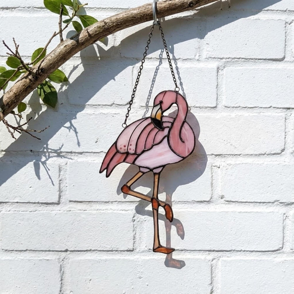 Pink stained glass flamingo suncatcher hanging in window casting vibrant colored shadows tropical beach house decor handmade gift for mom by LuzyGlassArt.