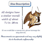 Handmade stained glass owl suncatcher in brown and beige tones, perched on a branch, casting warm amber shadows on a white wall, Tiffany style soldering detail.