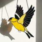 Stained glass American Goldfinch suncatcher hanging on window casting yellow shadows, vibrant yellow bird ornament for birdwatchers, handmade state bird gift for New Jersey Iowa Washington by LuzyGlassArt.