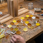 Handmade stained glass honeycomb bookends with metal bee detail, amber glass casting golden shadows, solid oak wood base for heavy books.