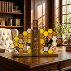 Handmade stained glass honeycomb bookends with metal bee detail, amber glass casting golden shadows, solid oak wood base for heavy books.