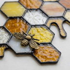 Handmade stained glass honeycomb bookends with metal bee detail, amber glass casting golden shadows, solid oak wood base for heavy books.