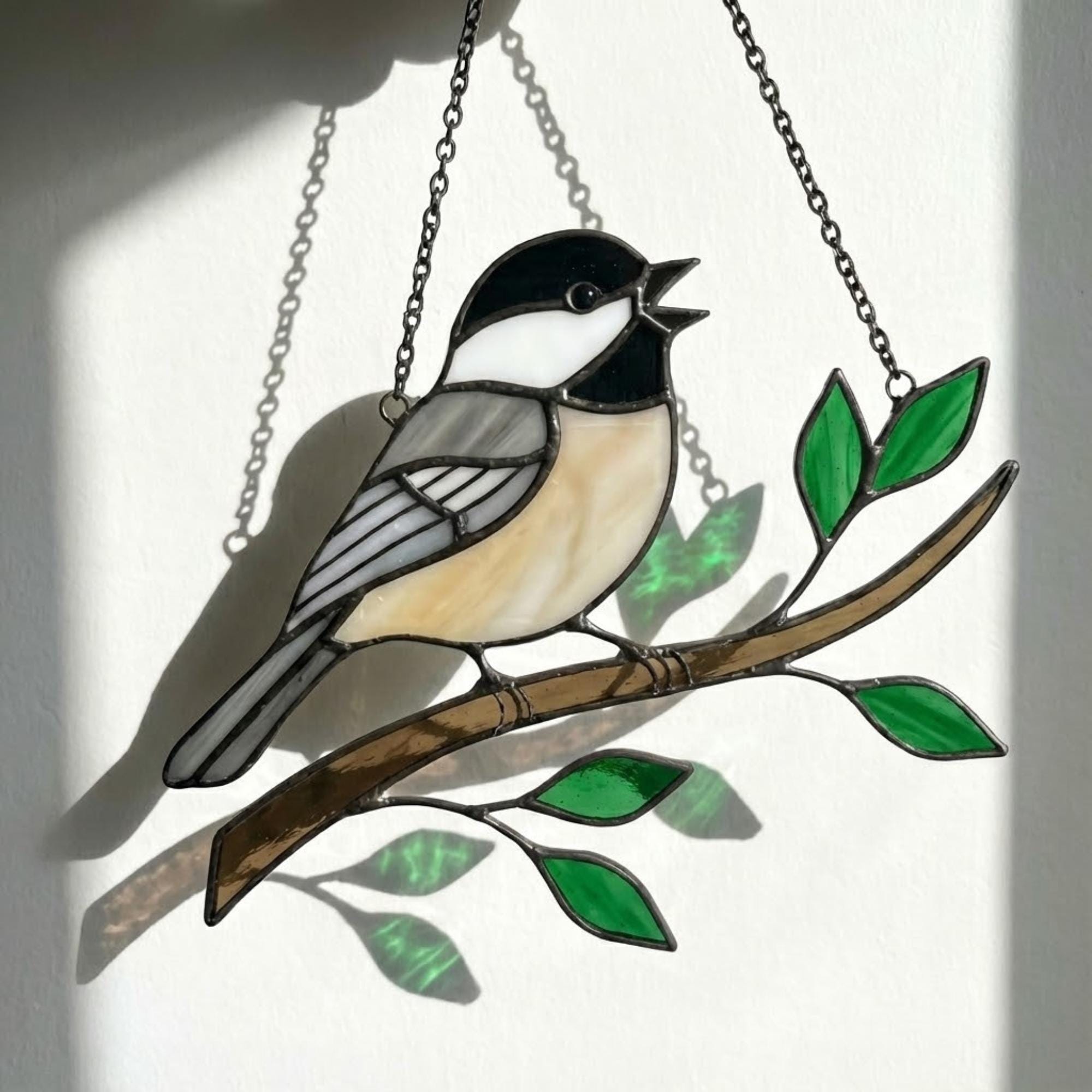 Stained glass Black-capped Chickadee bird suncatcher on branch hanging on window, handmade Maine and Massachusetts state bird gift, realistic nature decor by LuzyGlassArt.