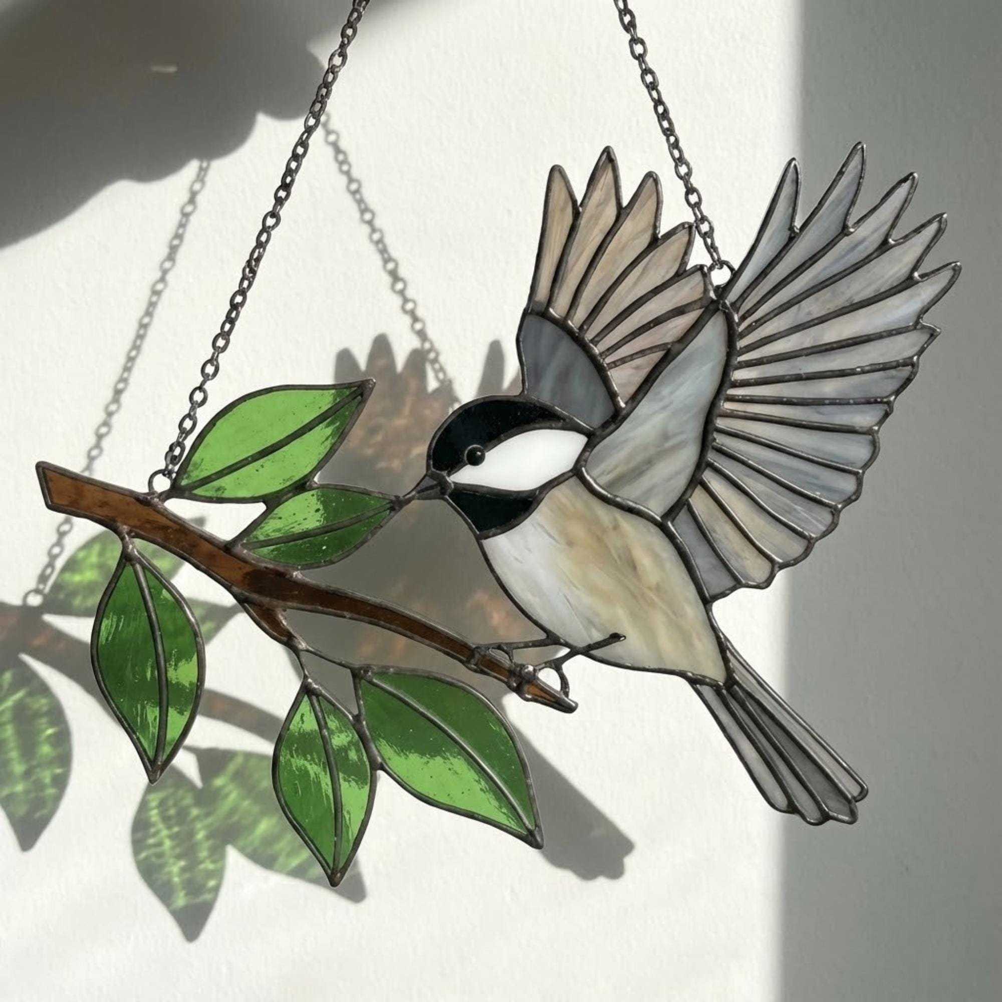 Stained glass Black-capped Chickadee bird suncatcher on branch hanging on window, handmade Maine and Massachusetts state bird gift, realistic nature decor by LuzyGlassArt.