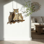 Handmade stained glass owl suncatcher in brown and beige tones, perched on a branch, casting warm amber shadows on a white wall, Tiffany style soldering detail.