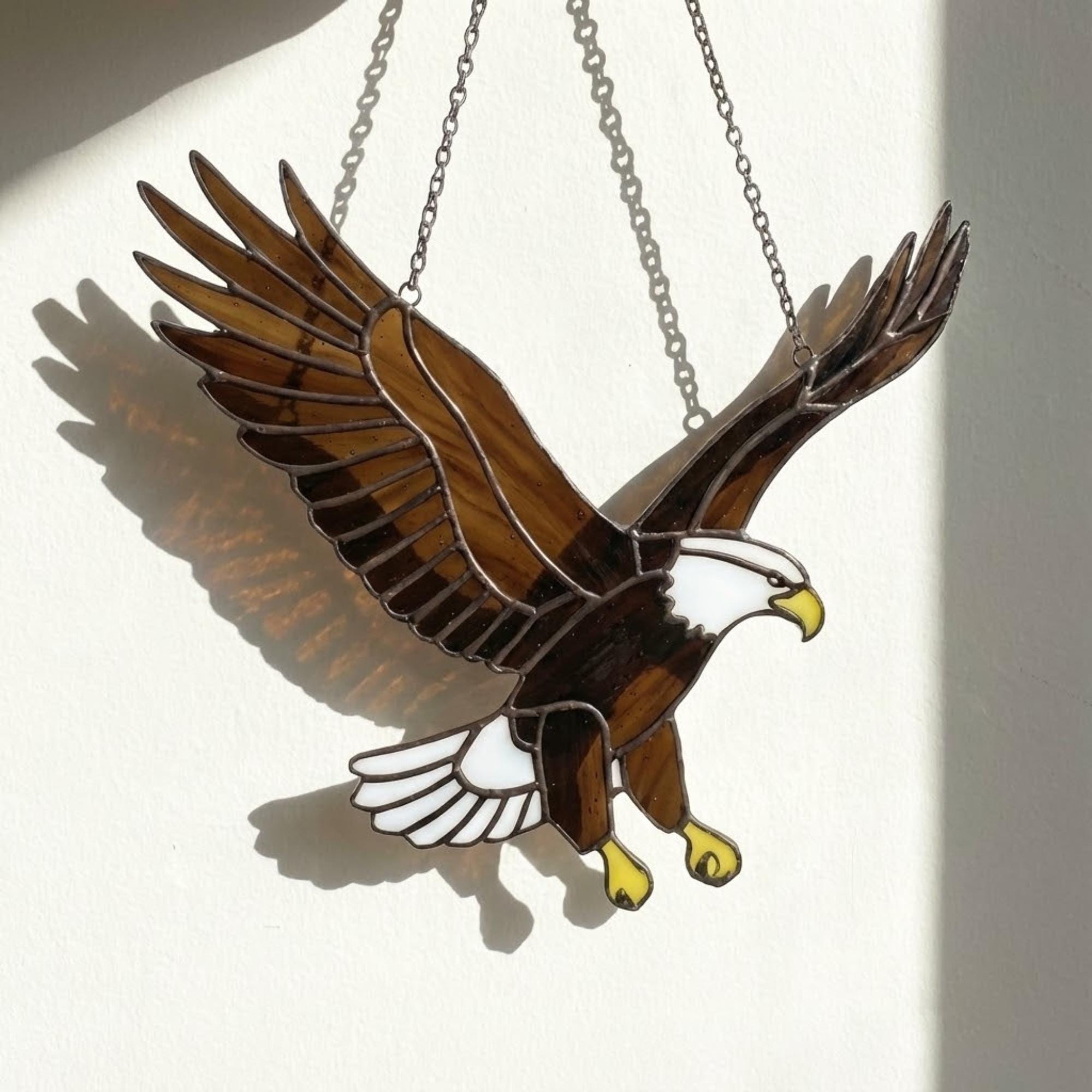 Handmade stained glass bald eagle suncatcher, realistic bird window hanging with brown and white glass, patriotic gift for dad or veteran, creating colored shadows.