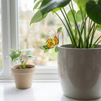 Handmade stained glass snail plant stake with amber shell and green leaves, cute cottagecore garden decor for indoor pots, gift for plant lover.