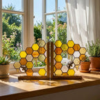 Handmade stained glass honeycomb bookends with metal bee detail, amber glass casting golden shadows, solid oak wood base for heavy books.