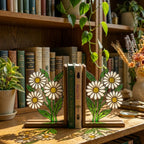 Handmade stained glass white daisy flower bookends on solid wood bases holding books on a sunlit desk, beautiful cottagecore shelf decor and book lover gift.
