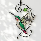 Handcrafted stained glass hummingbird and floral suncatchers in a circular metal hoop, casting colored shadows, packaged in a luxury wooden gift box for Mother's Day.