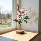 Handcrafted 3D stained glass pink cherry blossom sakura flower standing on a solid wooden base casting colored shadows on a desk, perfect Mother's Day gift.