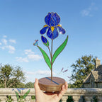 Handcrafted 3D stained glass blue iris flower standing on a wooden base with a brass nameplate, casting colored shadows, perfect Mother's Day desk decor gift.
